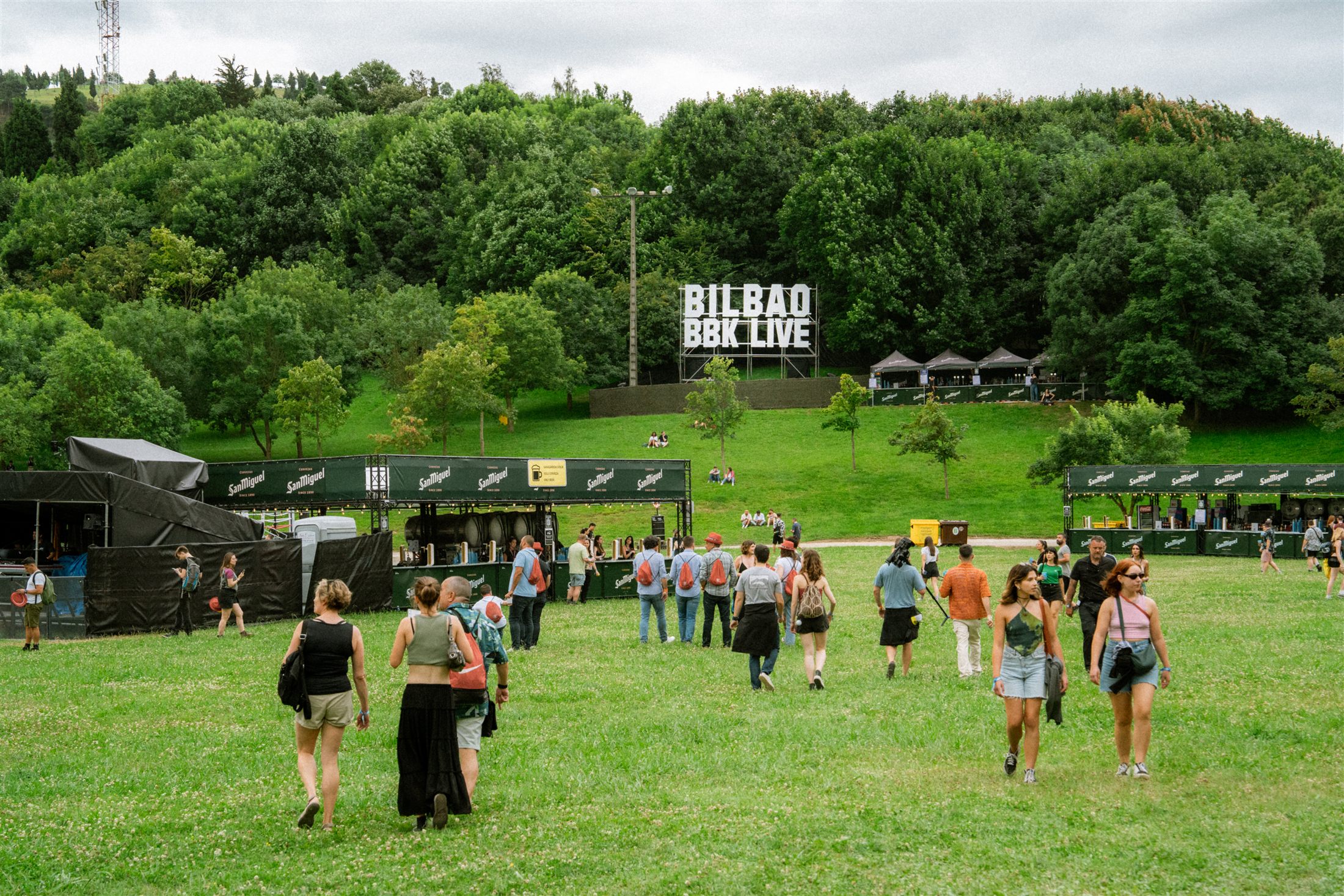 Público caminando por el recinto de Bilbao BBK Live 2024 con el cartel del festival al fondo - fotografía de Noland Live
