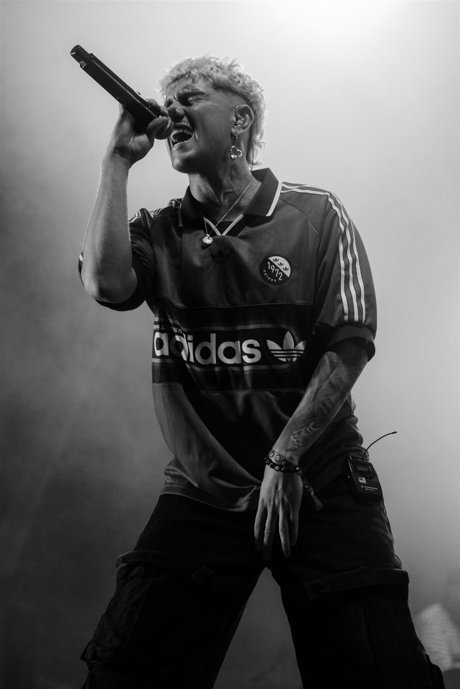 Cantante tatuado gritando al micrófono en blanco y negro