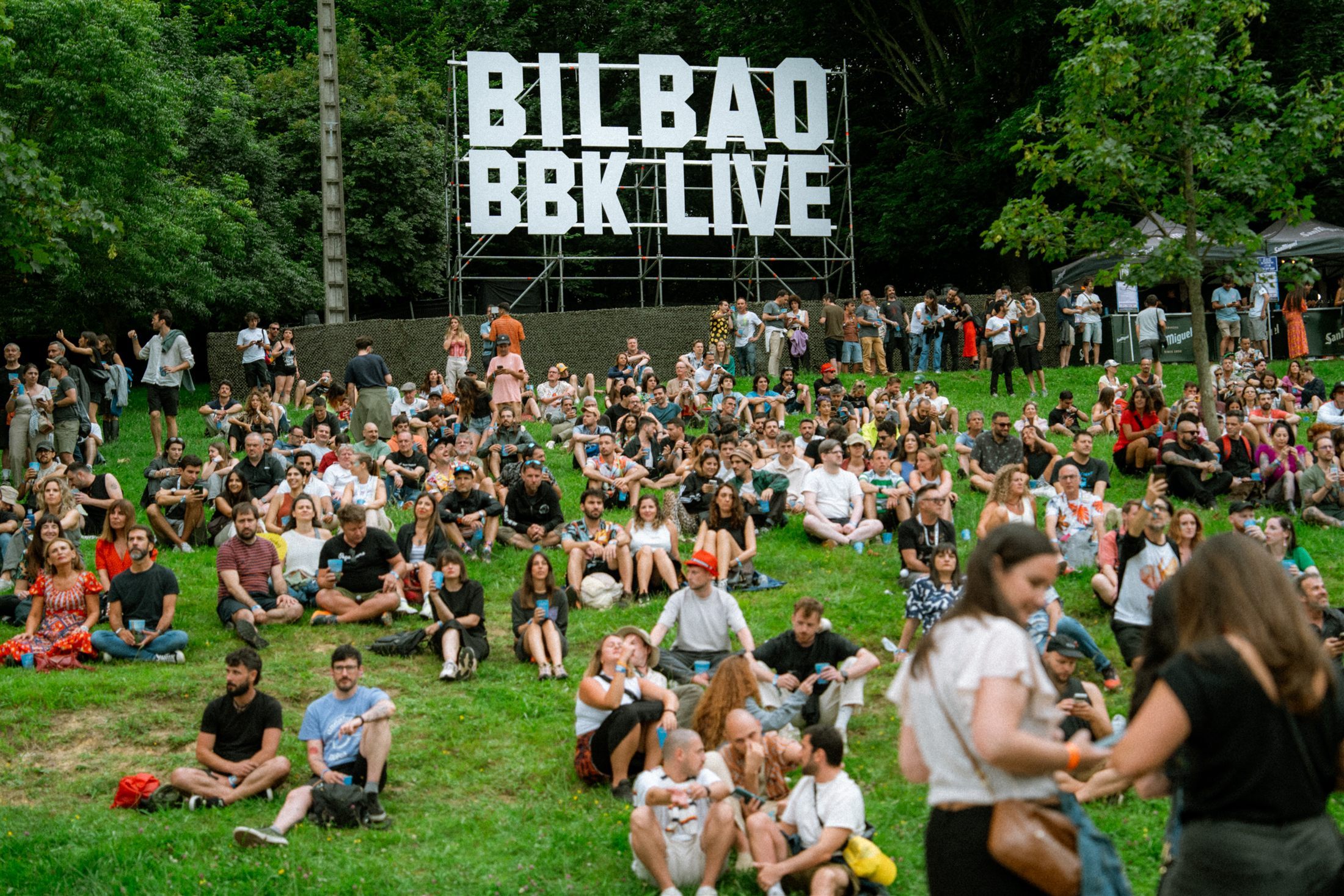 Cartel de Bilbao BBK Live junto al público sobre la hierba de Kobetamendi