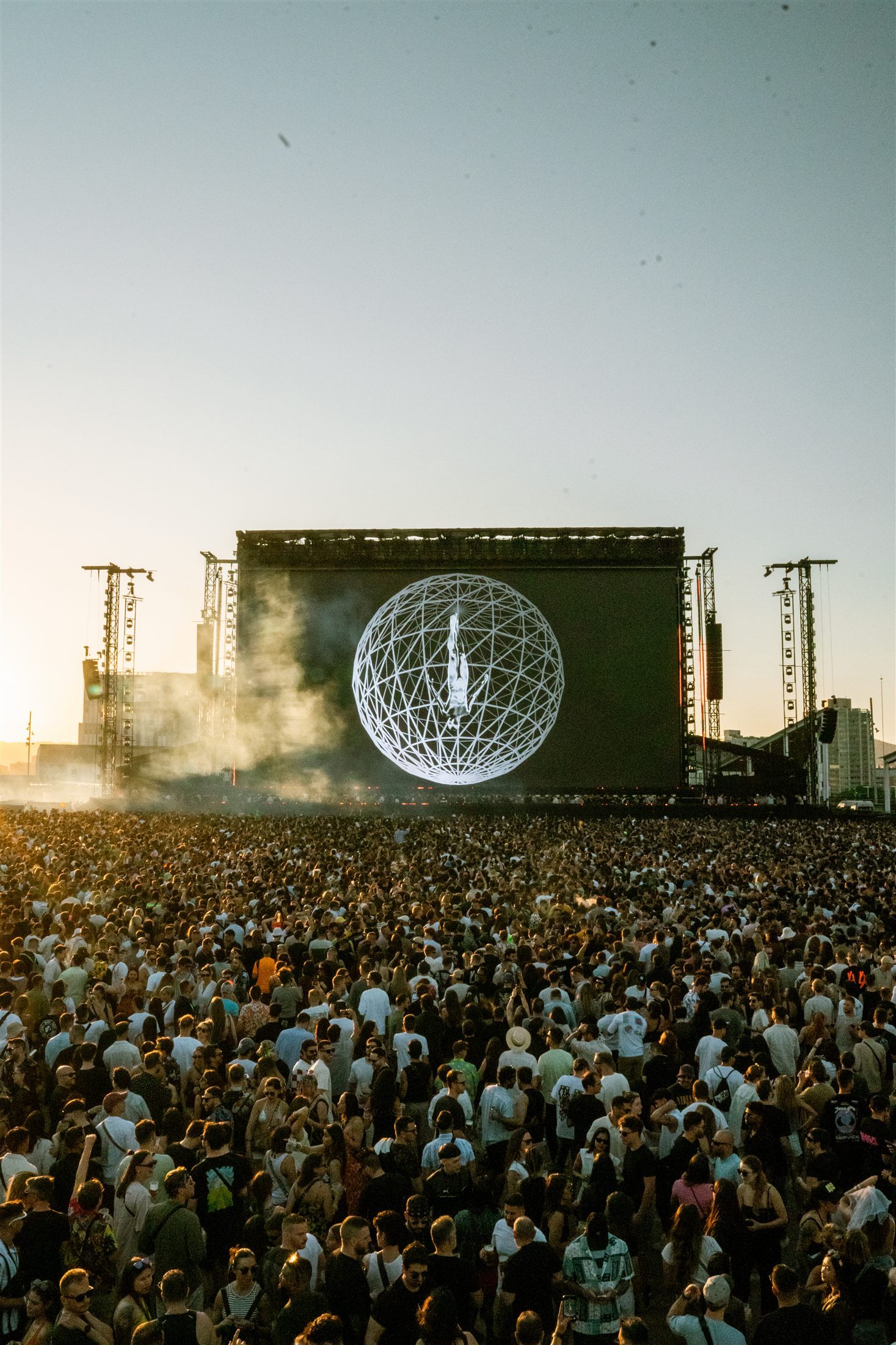 Escultura esférica iluminada sobre el escenario de Afterlife Barcelona con miles de personas al frente