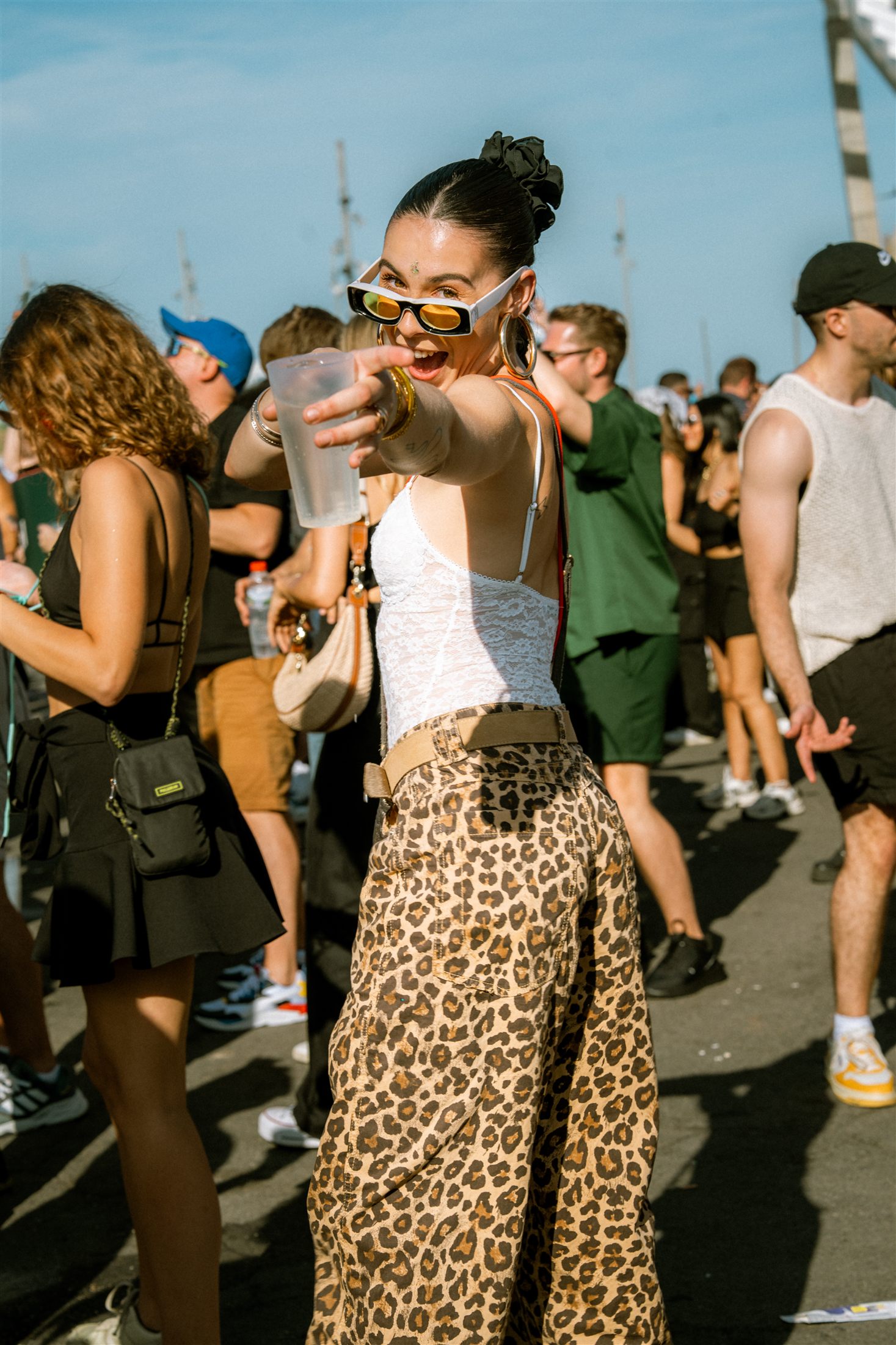 Asistente con estampado de leopardo señalando a cámara con una bebida en la mano