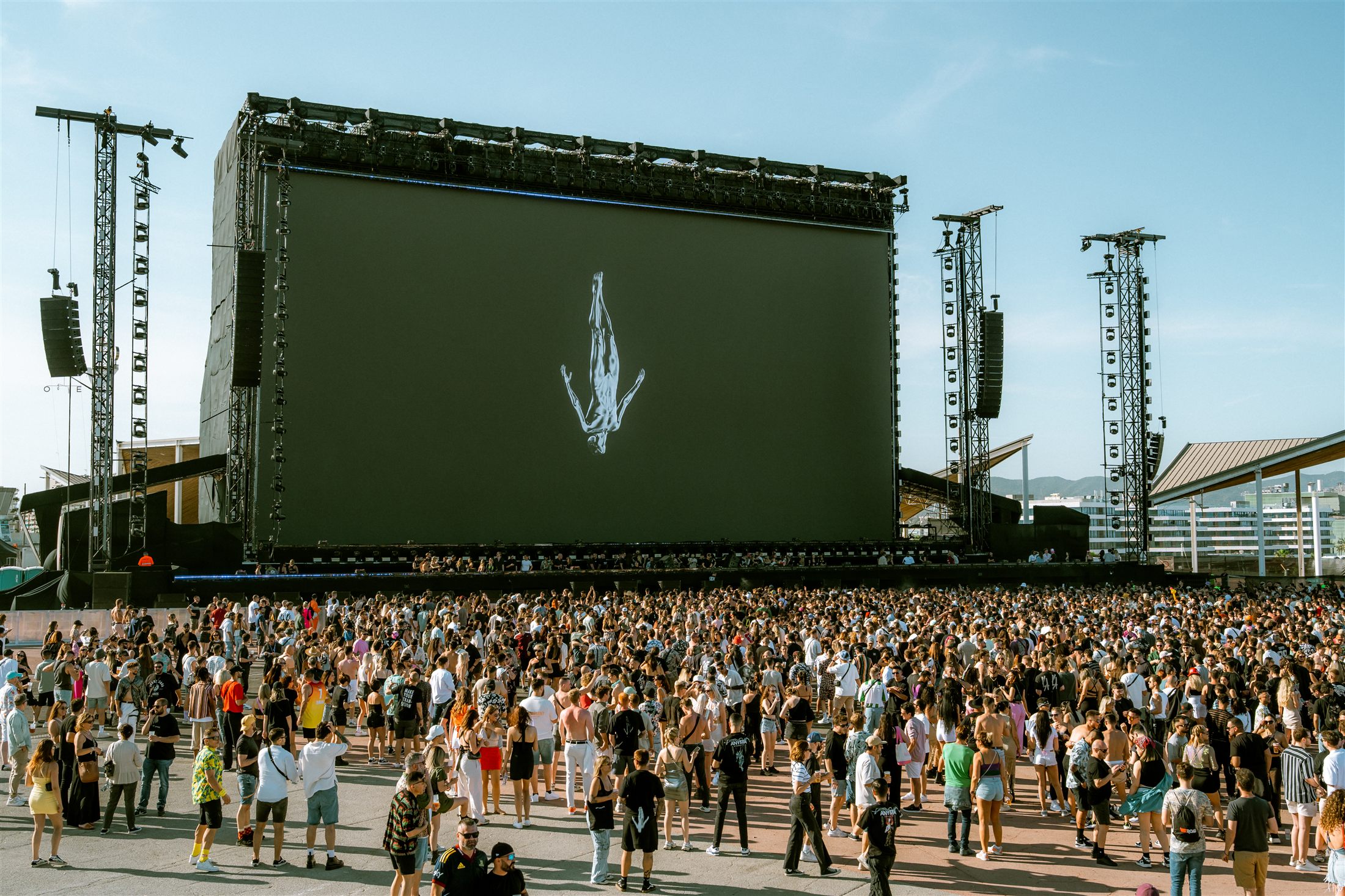 Figura invertida proyectada en la pantalla gigante de un festival