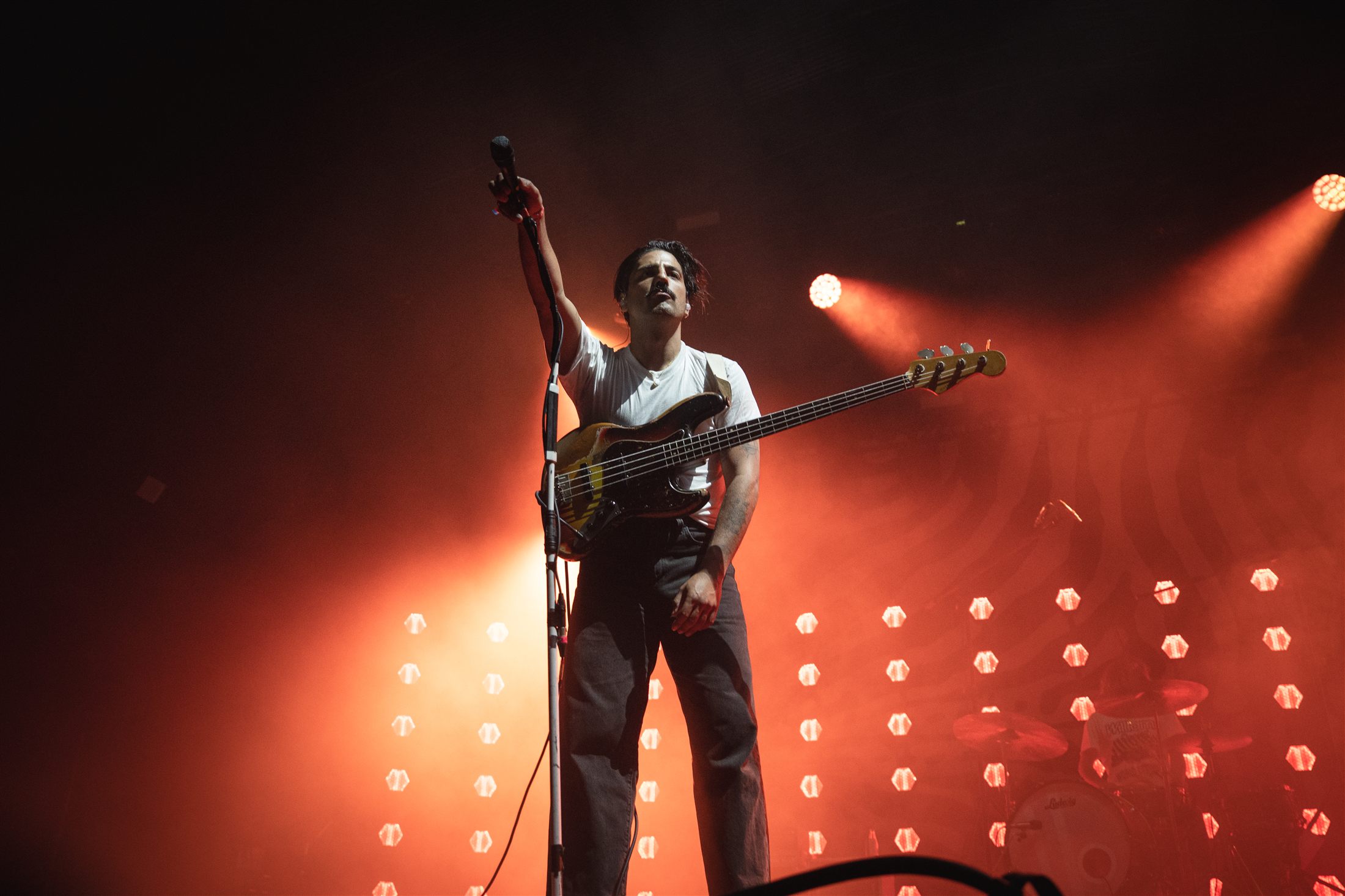 Bajista actuando en directo bajo un patrón de luces rojas