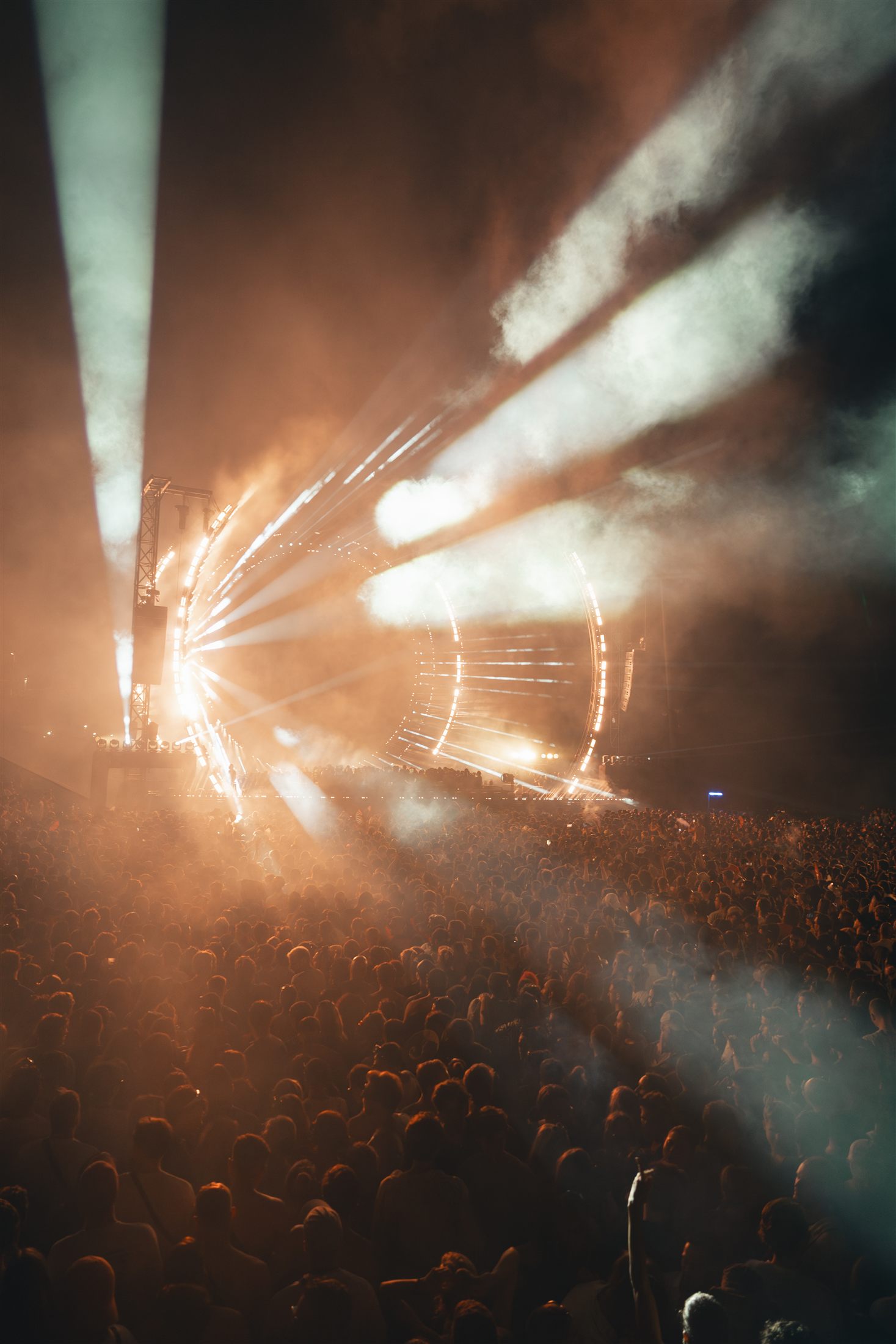Estructura circular de luces sobre el escenario entre humo cálido y multitud